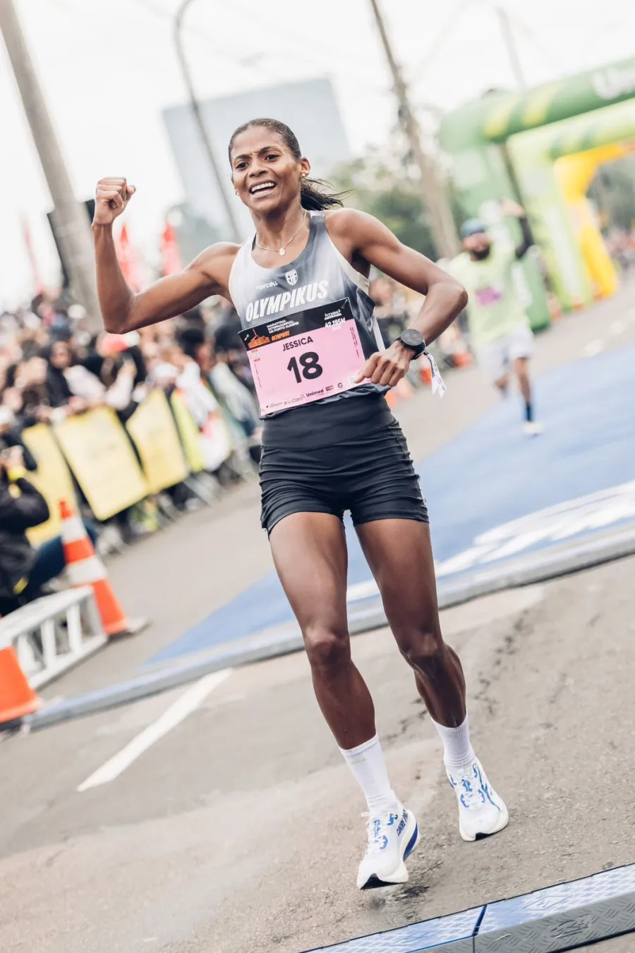 Jéssica comemora de punho cerrado na chegada da Maratona de Porto Alegre, com o número 18